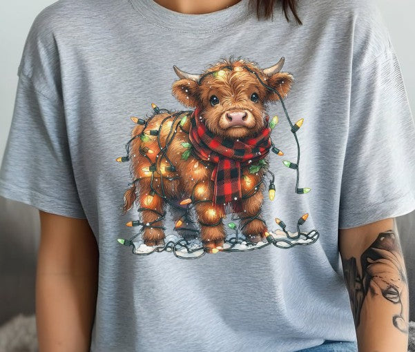 Festive Highland cow shirt wrapped in twinkling Christmas lights