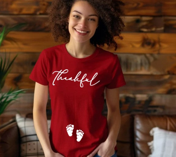 Thankful pregnancy announcement shirt with baby footprints on the belly
