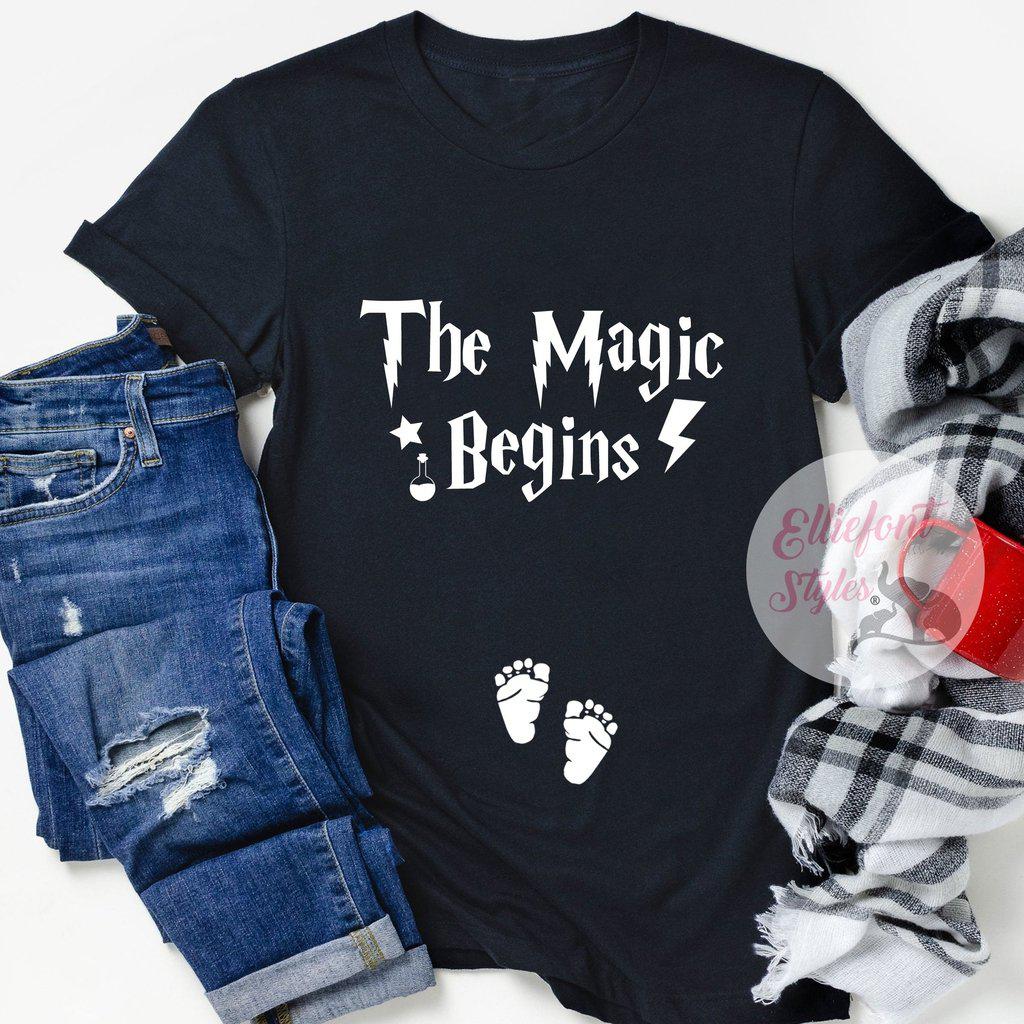 The Magic Begins pregnancy announcement shirt with baby footprints on the belly